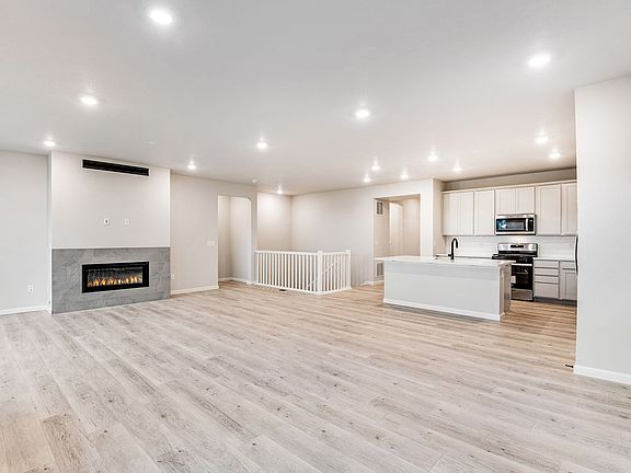 Great room and kitchen with modern fireplace and laminate wood look floors