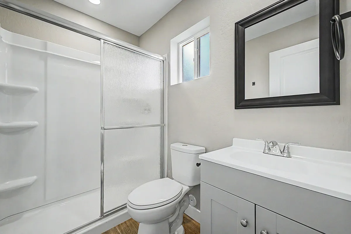 Clean full bath with tub/shower combo, sliding glass enclosure, vanity storage, and a frosted window for privacy. - E Princess Dr