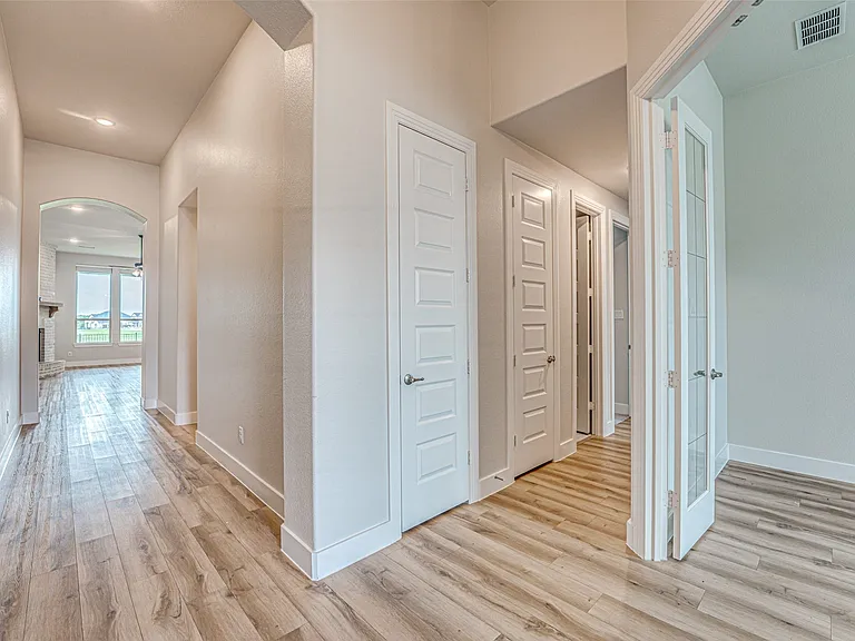 Hallway featuring wood-finish flooring, white baseboards, and an arched entryway