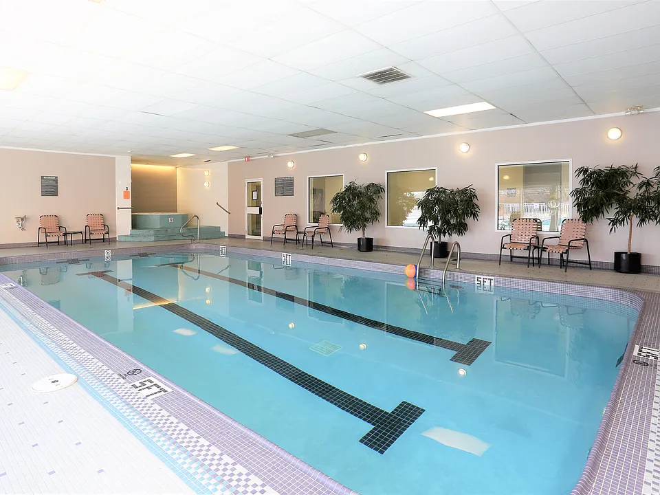 Elegant indoor swimming pool area with comfortable seating and lush greenery, perfect for relaxation and leisure.