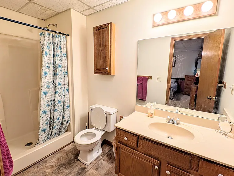 Full bathroom with tub/shower combo, vanity with storage, and a wide mirror with overhead lighting for daily routines.