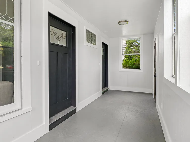 Sunroom space/closed in porch leading to attractive front doors of each unit of the two flat.