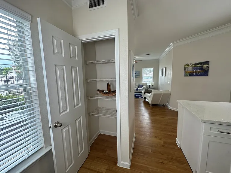 Bright, open-concept kitchen and living room with conveniently located pantry in a modern white kitchen with ample natural light through large windows. Bright, open-concept kitchen and living room with conveniently located pantry in a modern white kitchen
