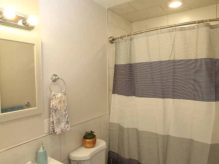 Clean full bathroom with tiled tub and shower
