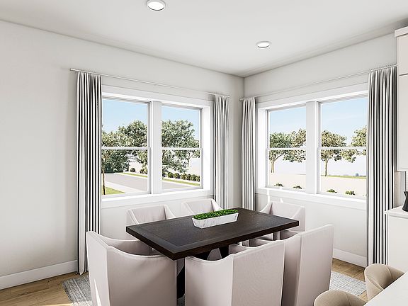 A bright and airy dining area with large windows overlooking a lush outdoor landscape, featuring a w