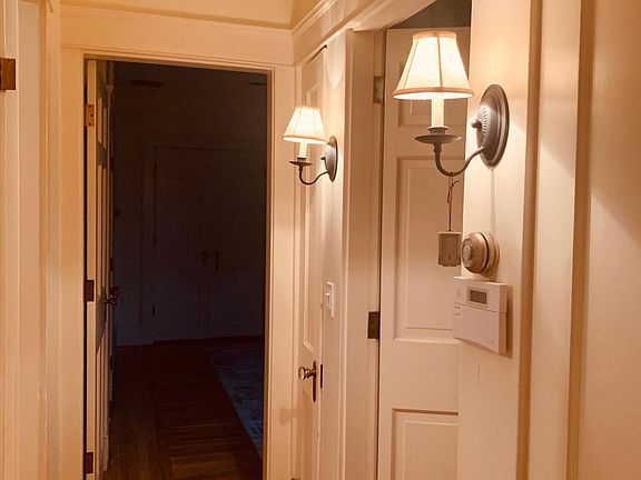 Hallway view leaving the office space of lit sconces outside the bathroom (on the right) with the master bedroom ahead. French doors (unseen on the left) lead to the front hallway, dining and living rooms. Linen closet ahead on right.