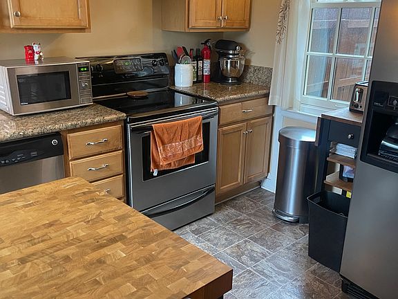 Kitchen with granite counters, lots of cabinetry. refrigerator, electric stove, dishwasher