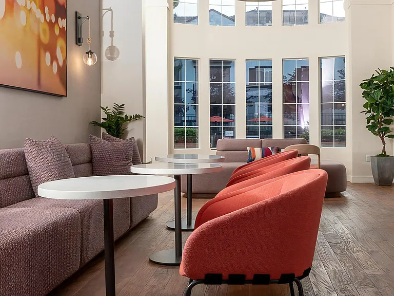 "Resident Lounge Featuring Cozy Seating, Dining Tables, and Tall Windows "