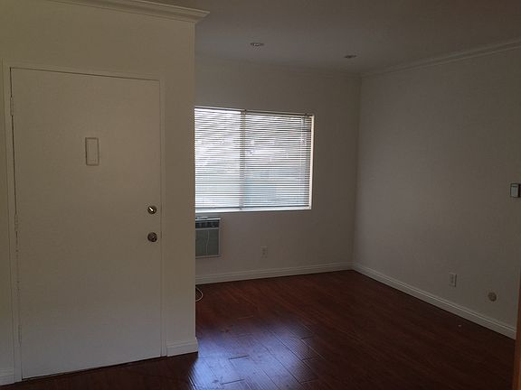 Unit 5 front door and living room with AC and window.