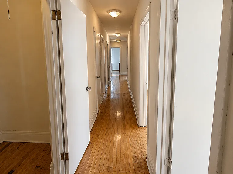 Hallway with kitchen at the end of the hall. Door on right is smallest of the 3 bedrooms. Room to the left is the hallway closet
