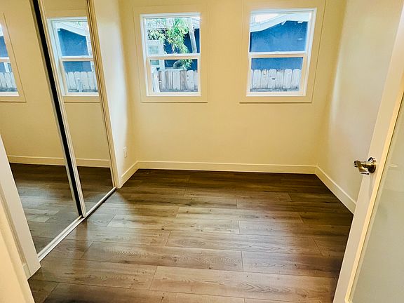 Lower unit bedroom with ceiling fan and mirrored closet doors.