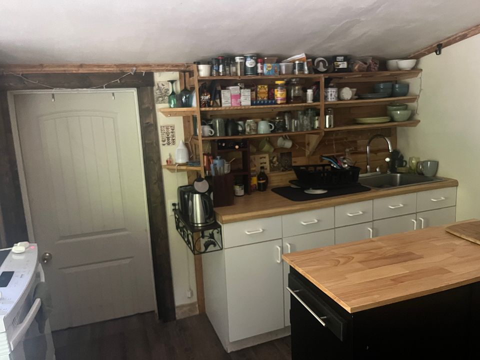 Kitchen with open shelving, butcher block island, full size stove and oven, refrigerator