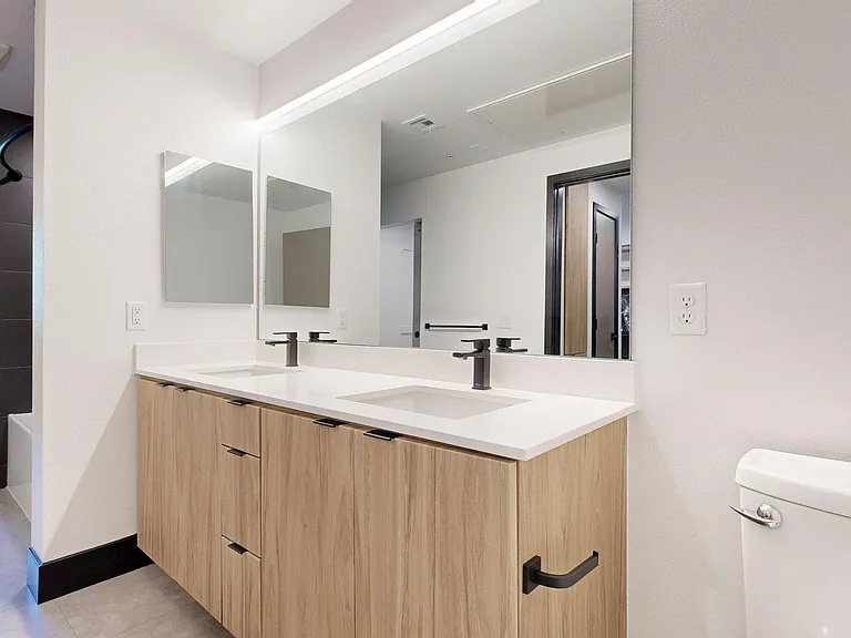 Apartment bathroom with LED lighted mirror and tile floor.