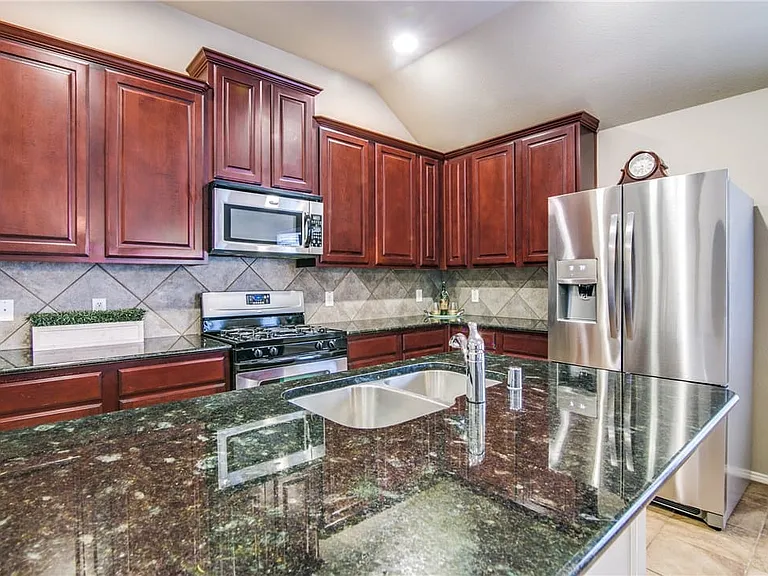 Large island with granite countertops stainless steel appliances. Fridge stays with the property.