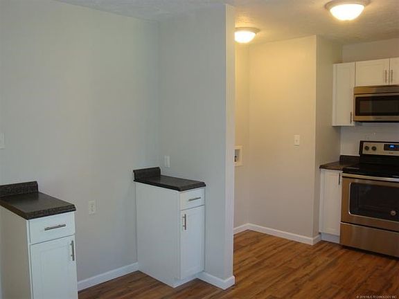 Refrigerator area in kitchen, nicely flanked by 2 base cabinets. Utility area to right of refrigerator.