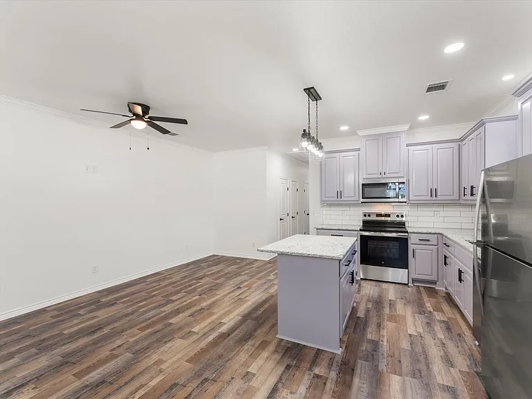 Modern kitchen featuring lavender cabinetry, stainless steel appliances, white subway tile backsplash, and light granite countertops