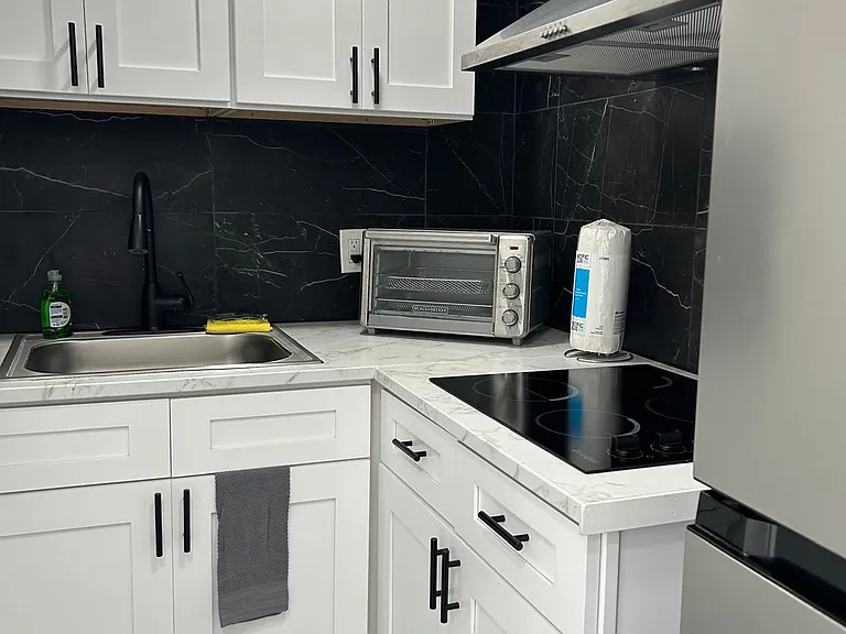 Fully equipped kitchen with drawers, sink, fridge, microwave, coffee maker, and stove.