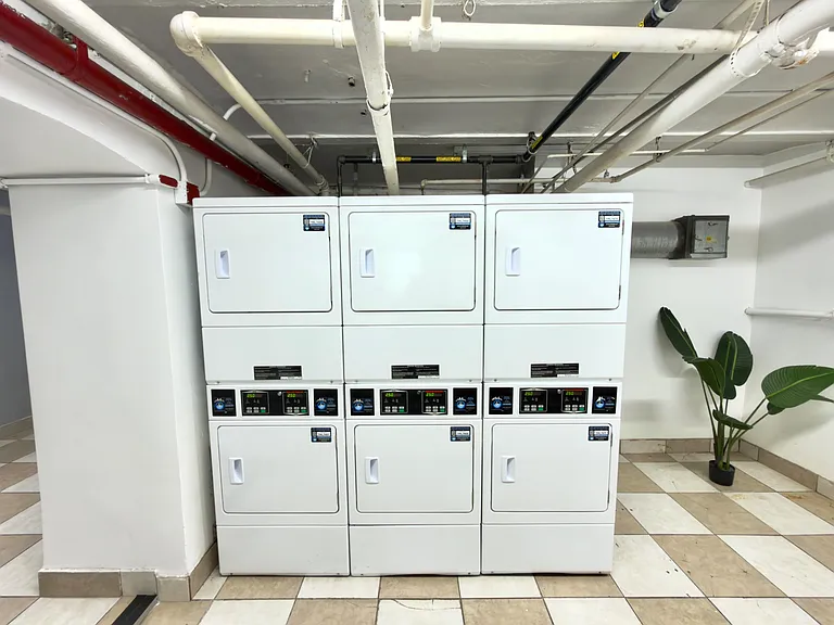 Shared laundry area with multiple on-site machines and a tiled floor for easy upkeep and convenient access.