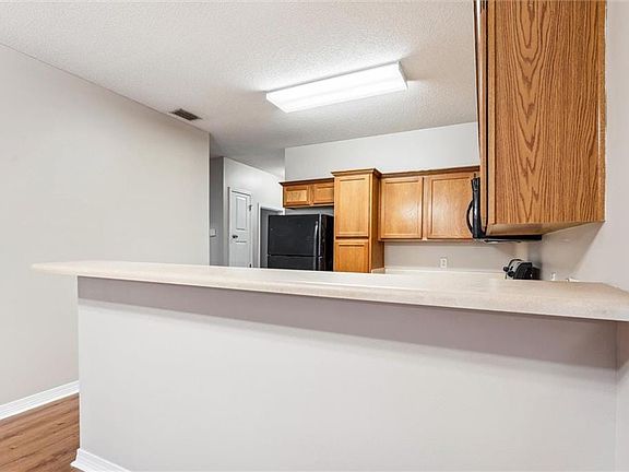 Kitchen featuring light wood-type flooring, kitchen peninsula, black refrigerator, and a textured ceiling