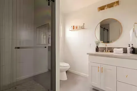 Bathroom 2
Bright bathroom featuring a white vanity, round mirror, and gold fixtures. A walk-in shower and natural light create a stylish, airy, and modern feel.
