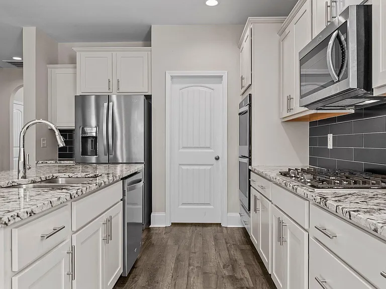 Kitchen with double oven, built-in microwave, fridge, gas top range and granite countertops.