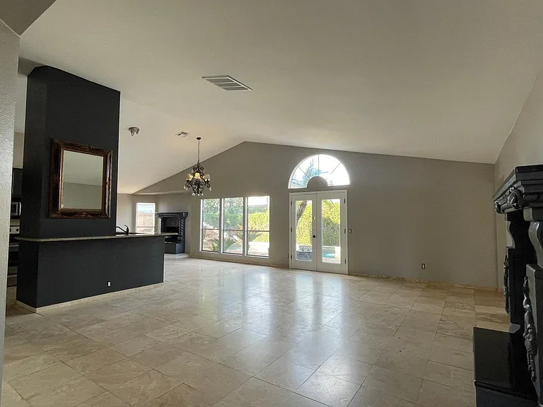 UNFURNISHED. Angle from the entrance of the property. Fire place on the right, kitchen counter on the left. Backyard on the foreground.