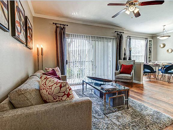 Living room with open dinning and kitchen areas, ceiling fan, balcony access and wood-style floors