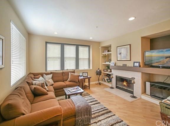 Living room offers lots of natural light, laminate wood floors, recessed lights & gas fireplace