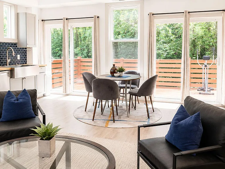 Open-concept living and dining area beside the kitchen, with large sliding doors to a private deck and ample natural light.