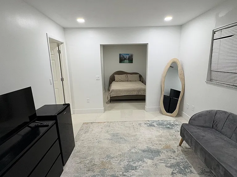 Open-concept suite with a lounge area, tile flooring, recessed lighting, and an adjoining sleeping nook.
