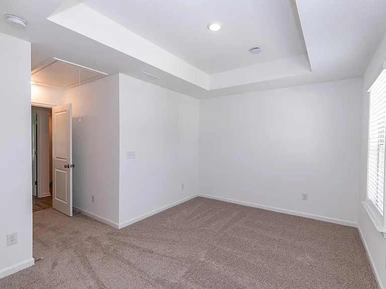 Secondary suite with plush carpet and windows for natural lighting.
