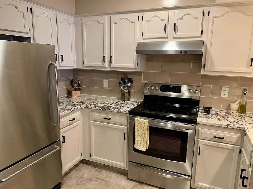 Granite countertops, Stainless steel appliances with black accents.