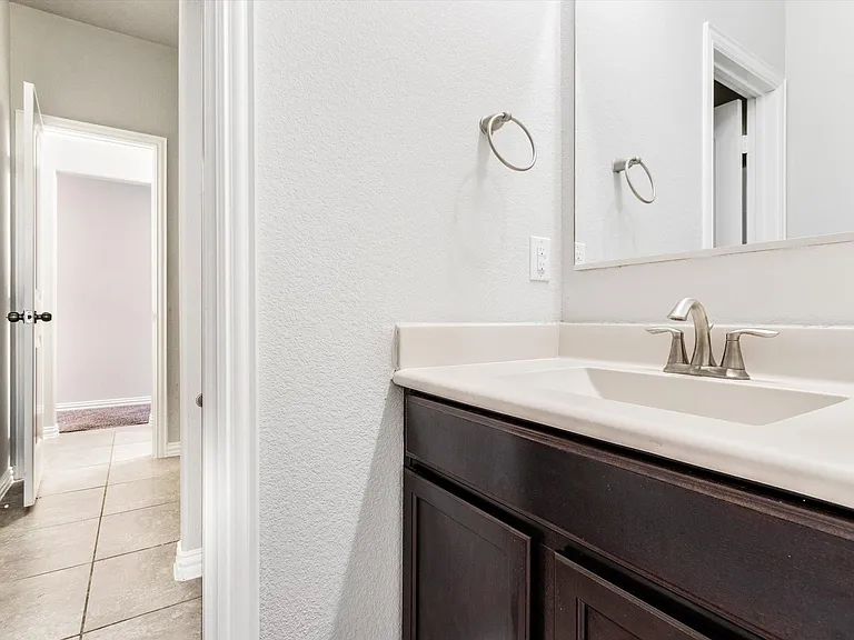 Bathroom vanity featuring a single basin sink, brushed nickel faucet, and dark wood-finish cabinetry