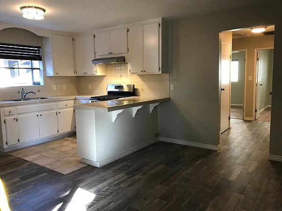Kitchen showing seating area at counter and part of living room and hallway.