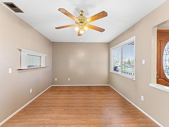 Formal dining room with fresh paint, new flooring, updated blinds and hardware, large ceiling fan with light, and a bright viewing window_perfect as a dining area, office, or creative space.