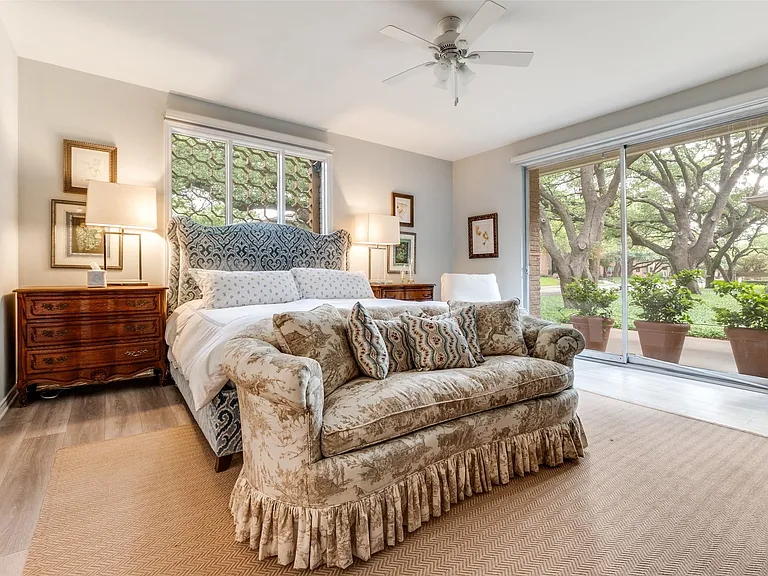 Spacious bedroom featuring wood-finish flooring, a ceiling fan, and large windows with transom above