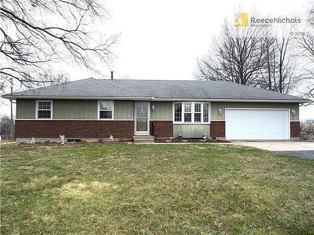 Ranch style home with metal siding and brick trim on 15 acres.