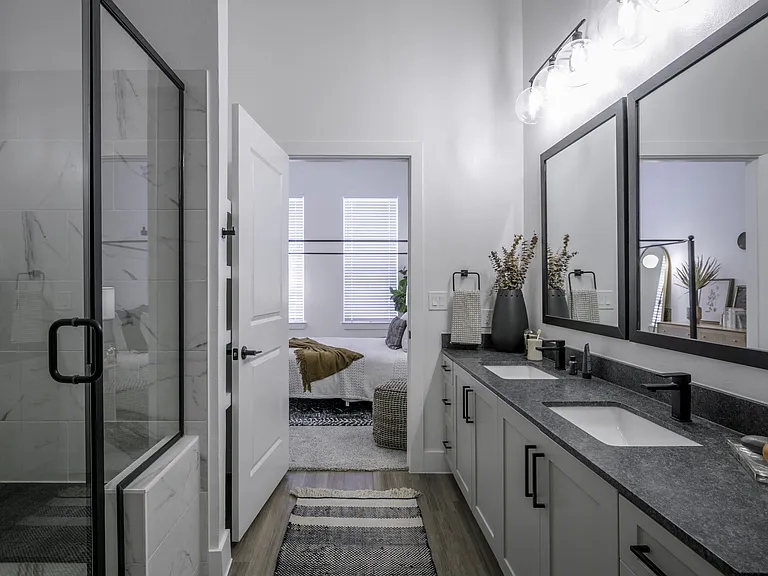 Step into luxury with standing showers embellished with striking black hardware, seamlessly blending modern design and functionality for a truly indulgent bathing experience.
