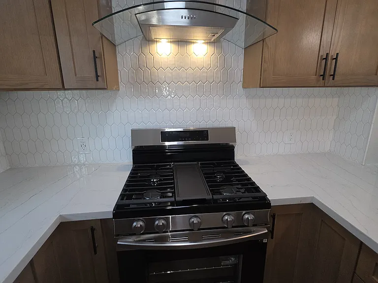 Kitchen cooking area including vent hood.
