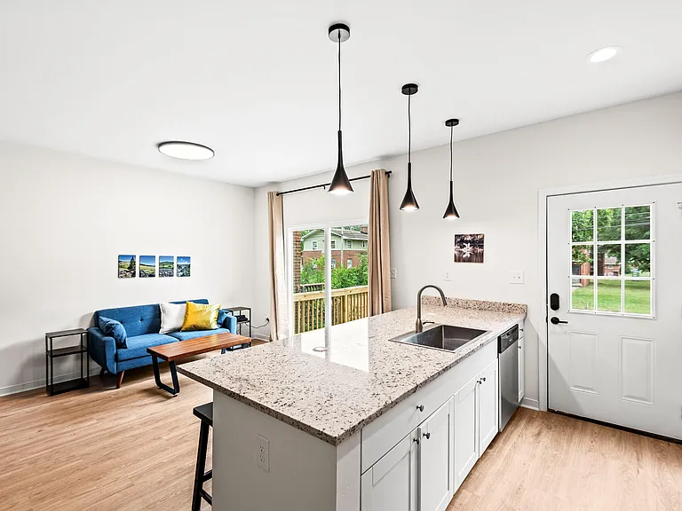Open kitchen with large island and sink, pendant lighting, and direct access to the patio through sliding doors.