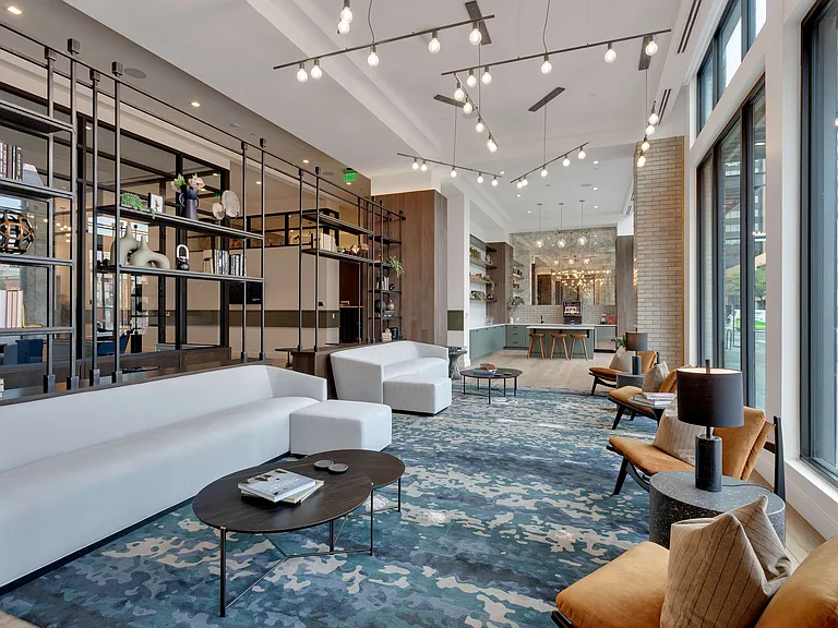 Elegant open-concept living space with modern furnishings, statement lighting, and floor-to-ceiling windows overlooking urban scenery.