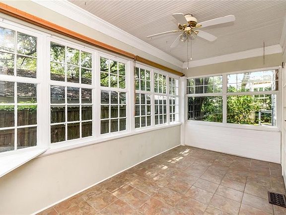 Sunroom featuring extensive grid-pattern windows, a beaded board ceiling, a ceiling fan, and tile flooring