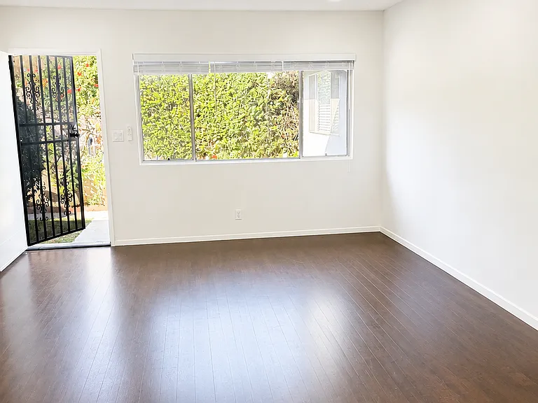 Spacious living area featuring a large window, natural light, and direct access to the exterior entry.