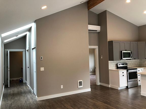 Looking from the living room area with kitchen on the right, bedroom in the middle, and entry way hallway on left. Unit has ductless heat pump above bedroom door that provides efficient heating and air conditioning. There are also electric heaters as back