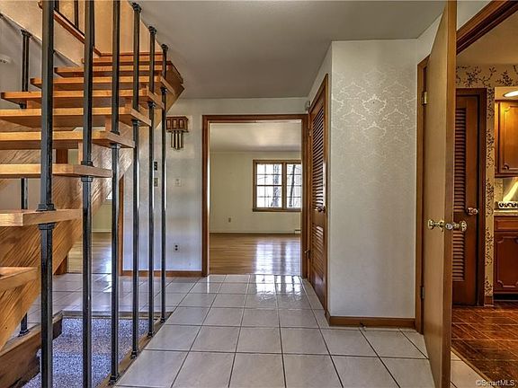 Front door entrance into home features open staircase and direct access to Living room, Kitchen and Den