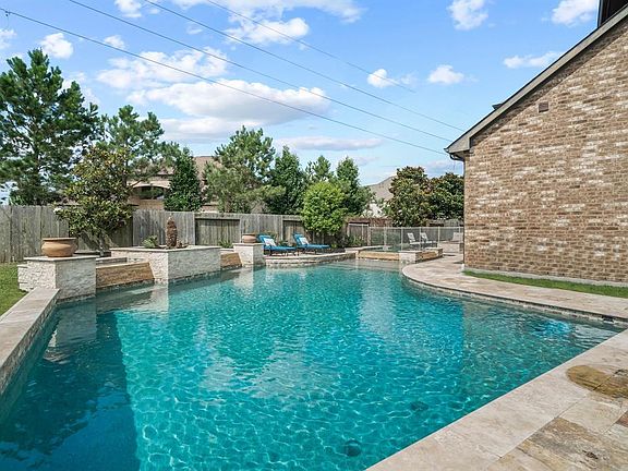 Sparkling pool and spa with travertine decking and removable safety fence ideally designed to separate the pool from the outdoor living space.