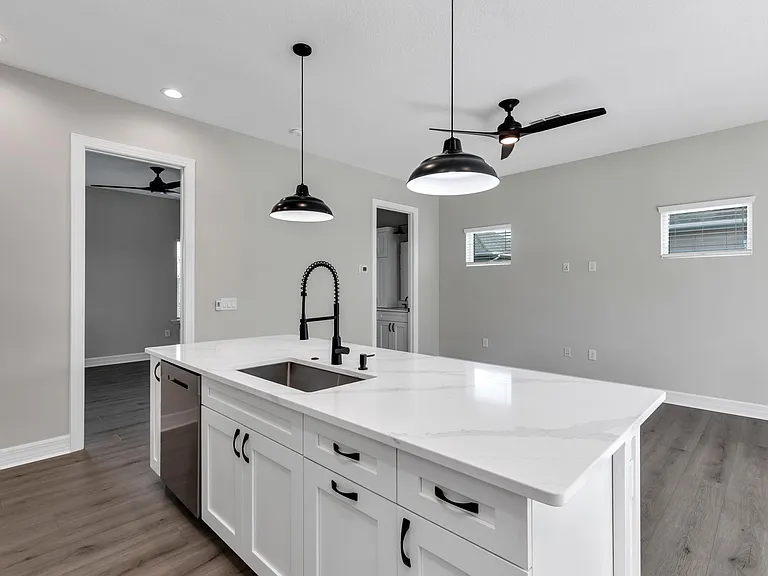 View of kitchen island facing south east from next to the laundry room. Notice the large sink, faucet, dishwasher, and tons more storage.