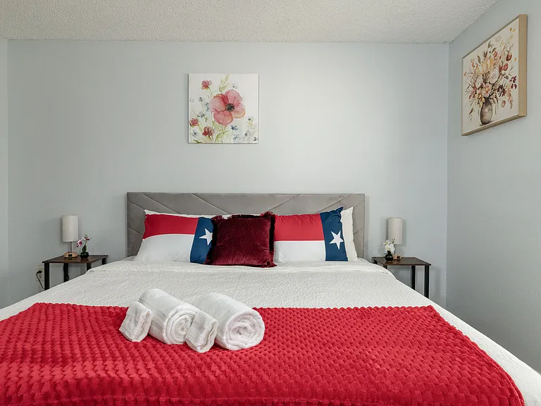 Relax in Bedroom 4, featuring a king bed with patriotic Texas flag pillows and a red throw.