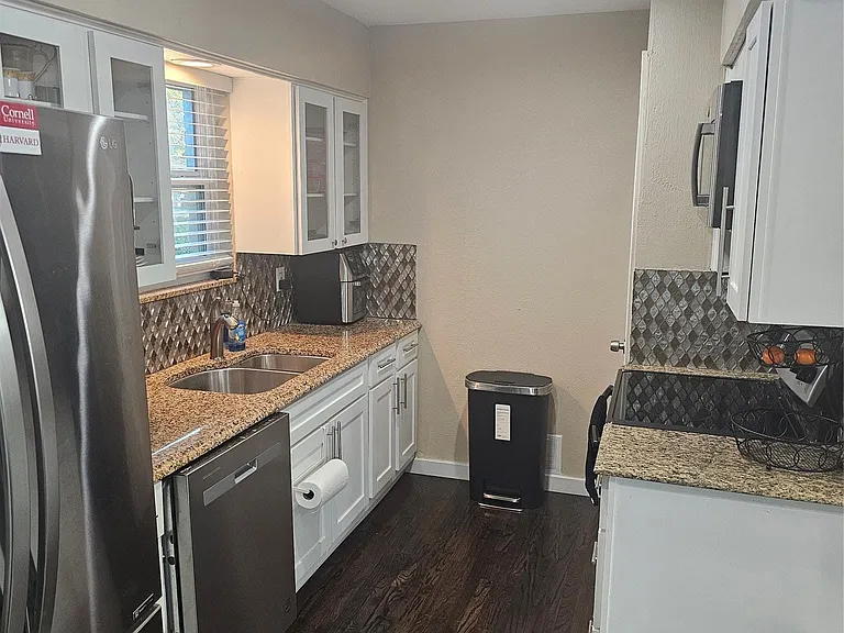 Kitchen with tasteful backsplash, light stone countertops, white cabinets, fridge, and recessed lighting
