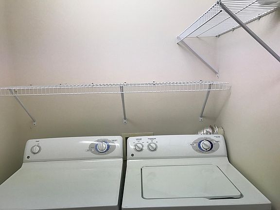 washer and dryer in unit with lots of shelf storage